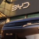 Frente de um carro da BYD cinza na frente da Concessionaria.