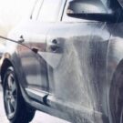 Carro cinza sendo lavado.