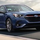 Frente de um Subaru Legacy azul na estrada.