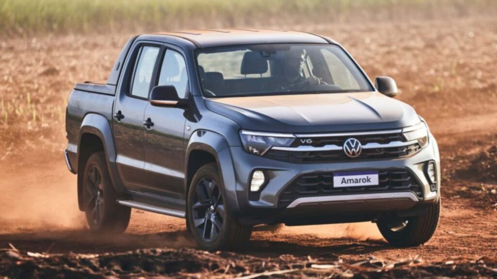 Frente da Amarok V6 2025 cinza escruo acelerando na estrada de terra.
