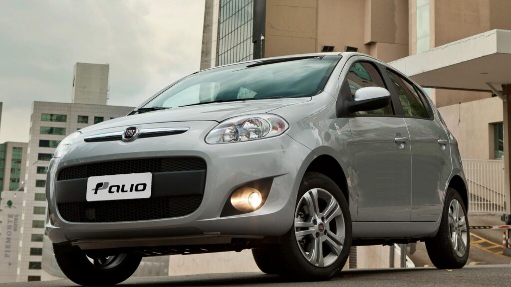 Fiat Palio prata na diagonal em meio da estrada.