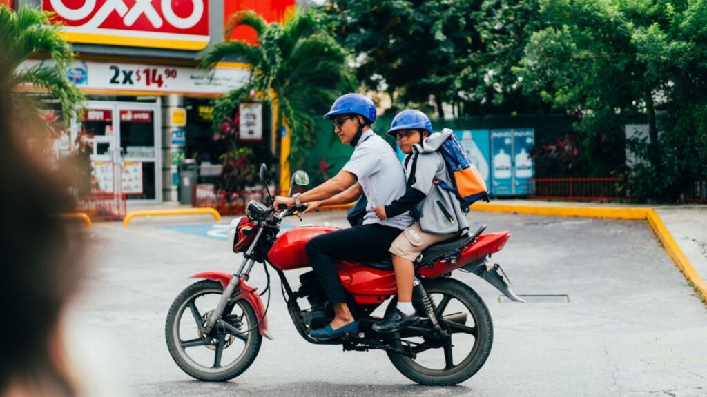 Um homem e uma criança em cima de uma moto vermelha, vendo acessórios para motos