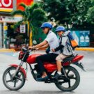 Um homem e uma criança em cima de uma moto vermelha, vendo acessórios para motos