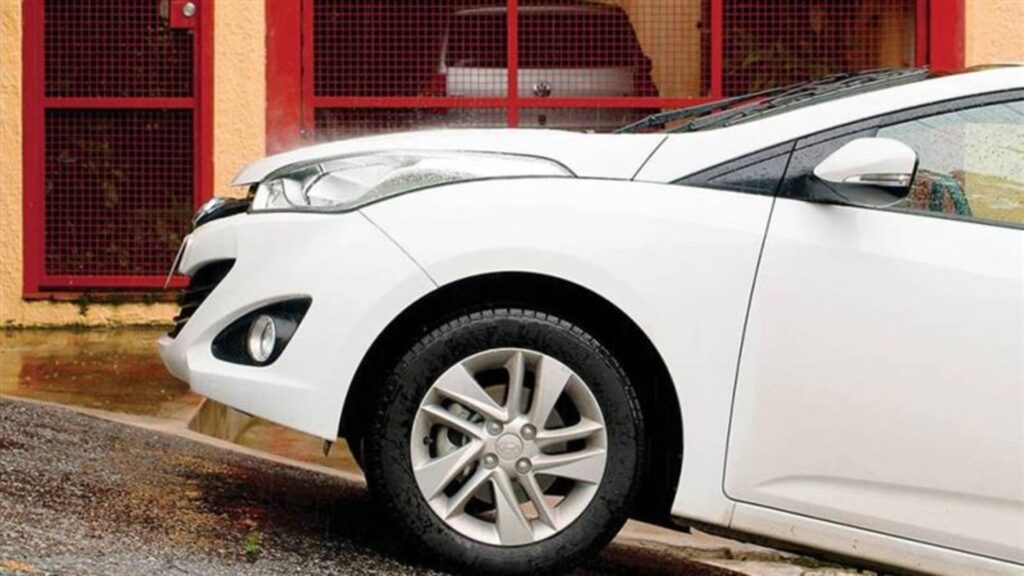 Dianteira de um carro branco parado em um morro.