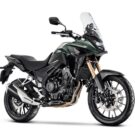 Honda CB 500X verde com preta parada na diagonal em um fundo branco.