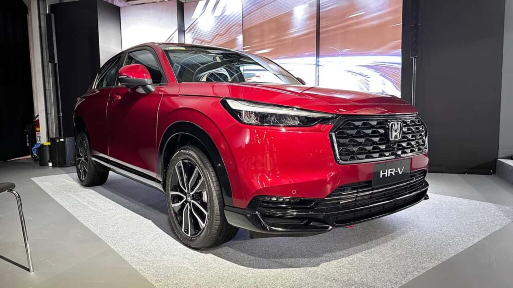 Honda HR-V 2026 vermelho na diagonal em uma exposição do lado de um telão.