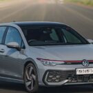 Volkswagen Golf GTI 2025 cinza parado na diagonal no meio da estrada.