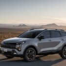 Kia Sportage cinza parado na diagonal em uma estrada.