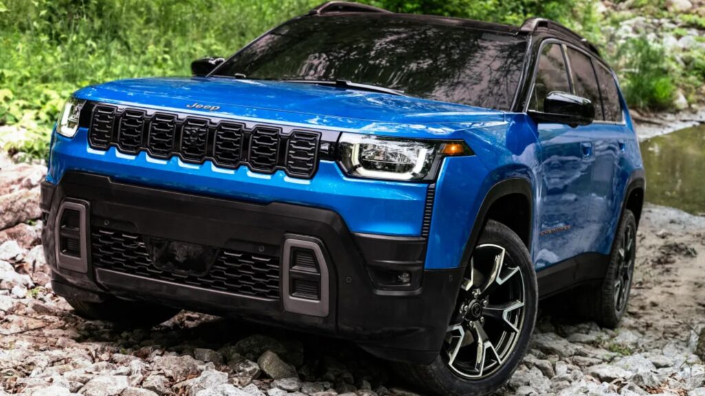 Nova geração do Jeep Cherokee azul parado em diagonal em cima de umas pedras.