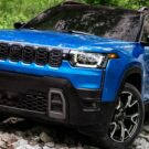 Nova geração do Jeep Cherokee azul parado em diagonal em cima de umas pedras.