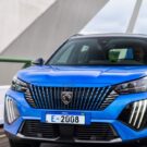 Frente do Peugeot e-2008 GT 2025 azul passando por uma ponte.