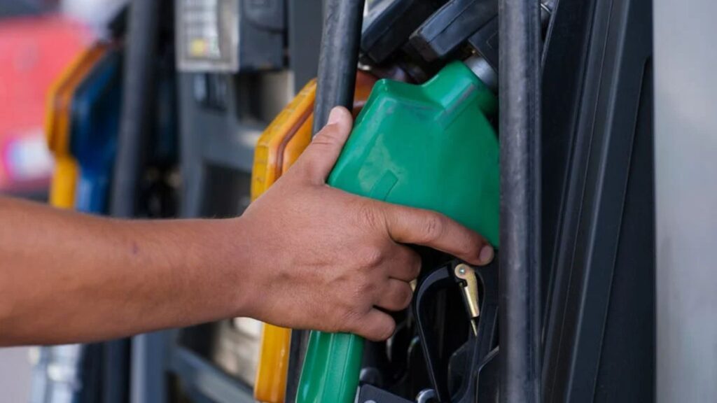 Pessoa segurando com a mão em uma pistola de uma bomba de gasolina.