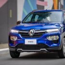 Renault Kwid 2026 azul na estrada com os faróis ligados.