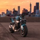 BMW F 900 R 2026 azul parada na diagonal em cima de um prédio com um por do sol no fundo.