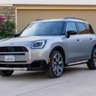 Mini Countryman 2026 cinza parado na diagonal em frente de uma garagem.