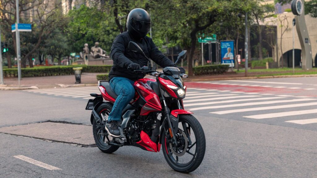 Bajaj Pulsar N150 vermelha em movimento na estrada.
