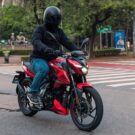 Bajaj Pulsar N150 vermelha em movimento na estrada.