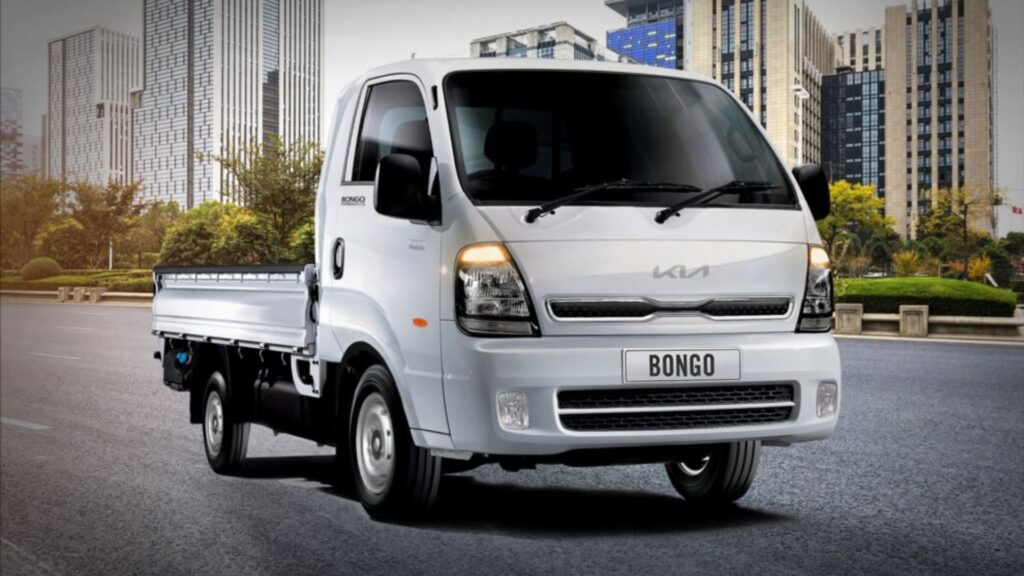 Novo Kia Bongo 4x4 2026 na estrada com os faróis acesos.