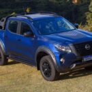 Nissan Frontier azul parada na diagonal em um gramado.
