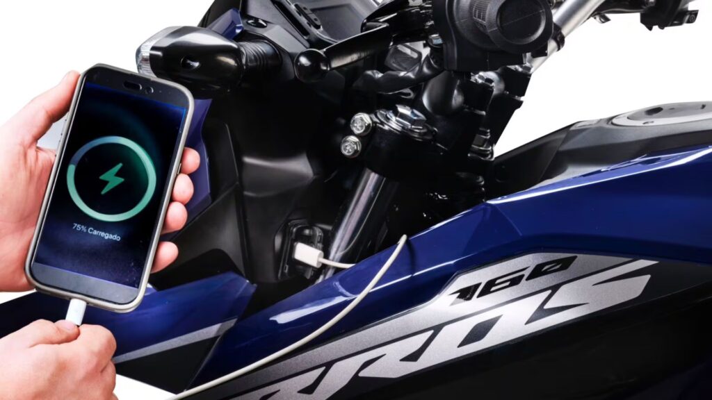 Pessoa carregando o celular na Honda NXR 160 Bros 2026.