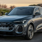 Audi Q5 2025 cinza em movimento em um asfalto com um por do sol no fundo.