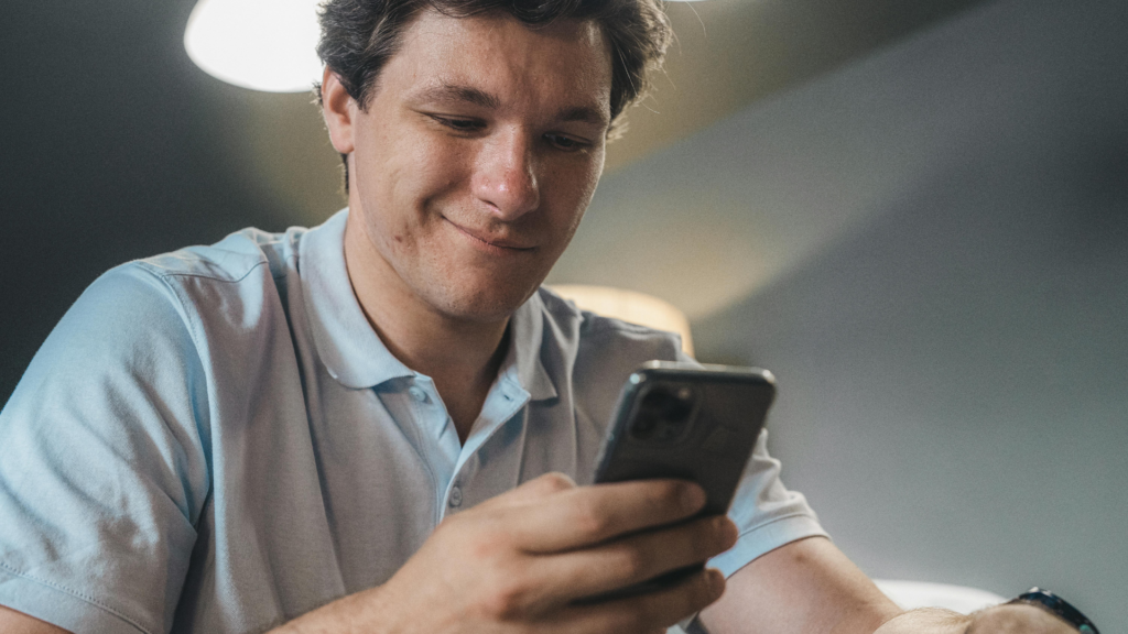 Homem sorrindo segurando seu celular.