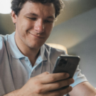 Homem sorrindo segurando seu celular.