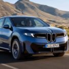 BMW iX3 2026 azul em movimento na estrada.