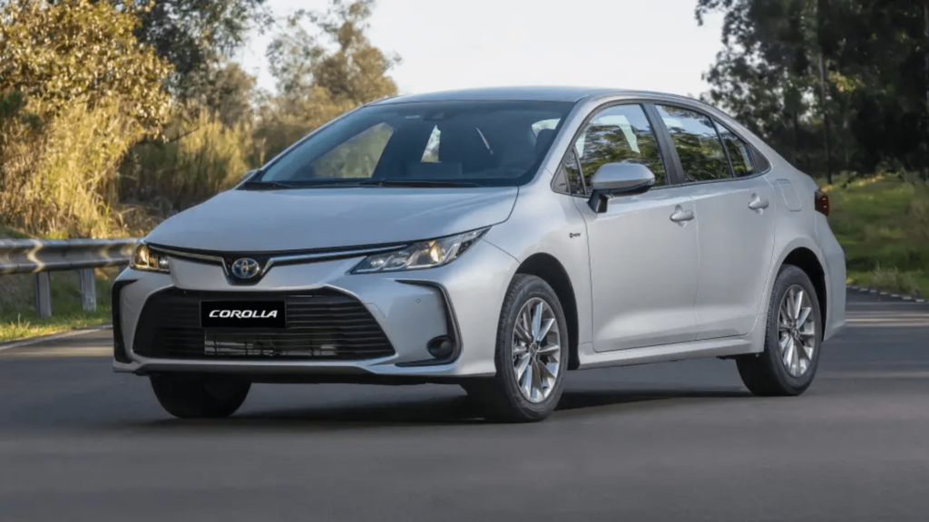 Toyota Corolla 2026 prata parado na diagonal no meio de um asfalto.