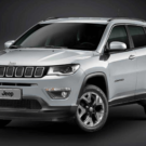 Jeep Compass branco parado na diagonal em um fundo preto.