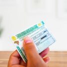 Pessoa segurando um documento verde chamado CNH com uma mesa na frente.