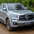 GWM Poer P30 prata em movimento na estrada de barro com uma vegetação verde no fundo.