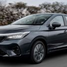 Honda City 2025 cinza em movimento no asfalto com árvores no fundo.