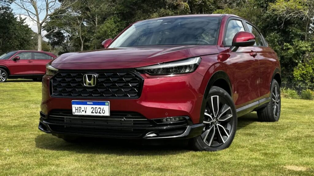Honda HR-V Touring 2026 vermelho parado na diagonal em cima de um gramado.