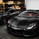 Dois carros de luxos pretos parados dentro de uma garagem.