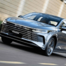 BYD King 2026 cinza acelerando na estrada com os faróis acesos.