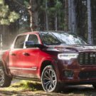 Ram 1500 vermelho parado na diagonal dentro de uma floresta.