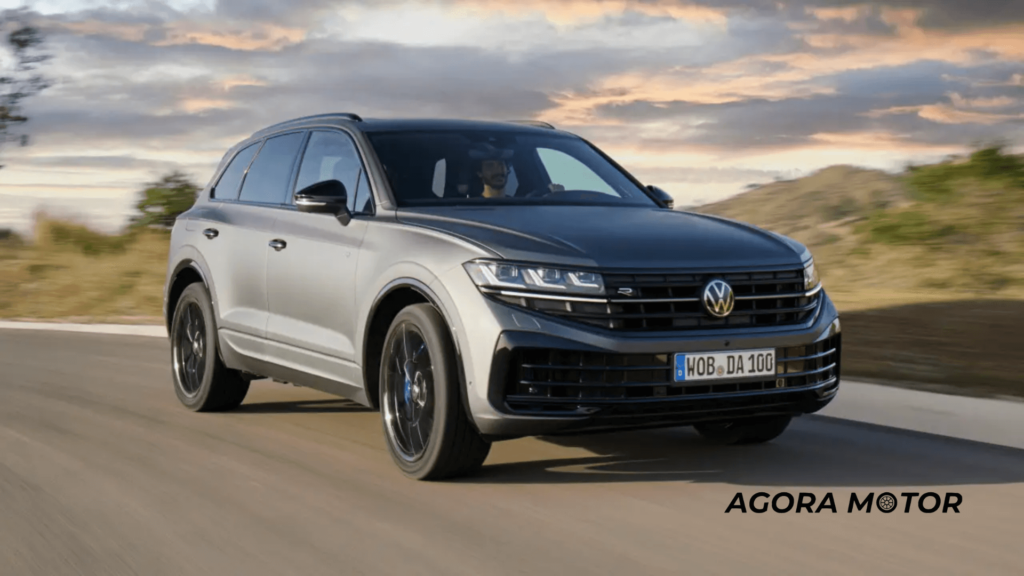 Volkswagen Touareg cinza de frente com um céu cheio de nuvens no fundo,