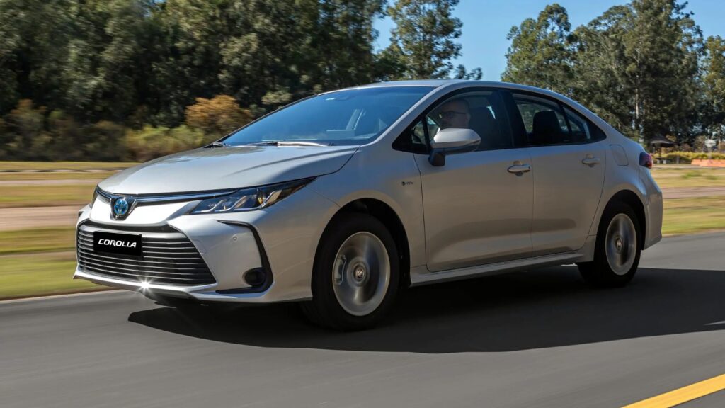 Toyota Corolla 2026 em movimento na estrada com uma floresta no fundo.