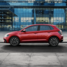 Lateral do Volkswagen Polo vermelho parado estacionado na beirada da estrada.