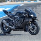 Yamaha R1 preta na diagonal no meio da pista.
