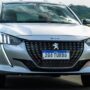 Frente do Peugeot 208 prata com os faróis acesos.