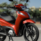 Honda Biz 125 vermelha parado na diagonal.