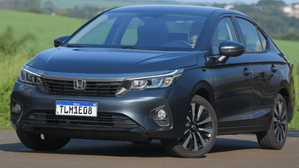 Honda City LX cinza parado na diagonal no meio da estrada.