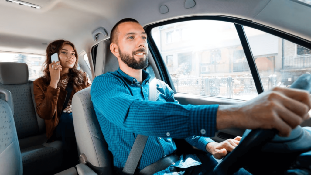 Homem que trabalha na Uber de azul com uma passageira no banco de trás.