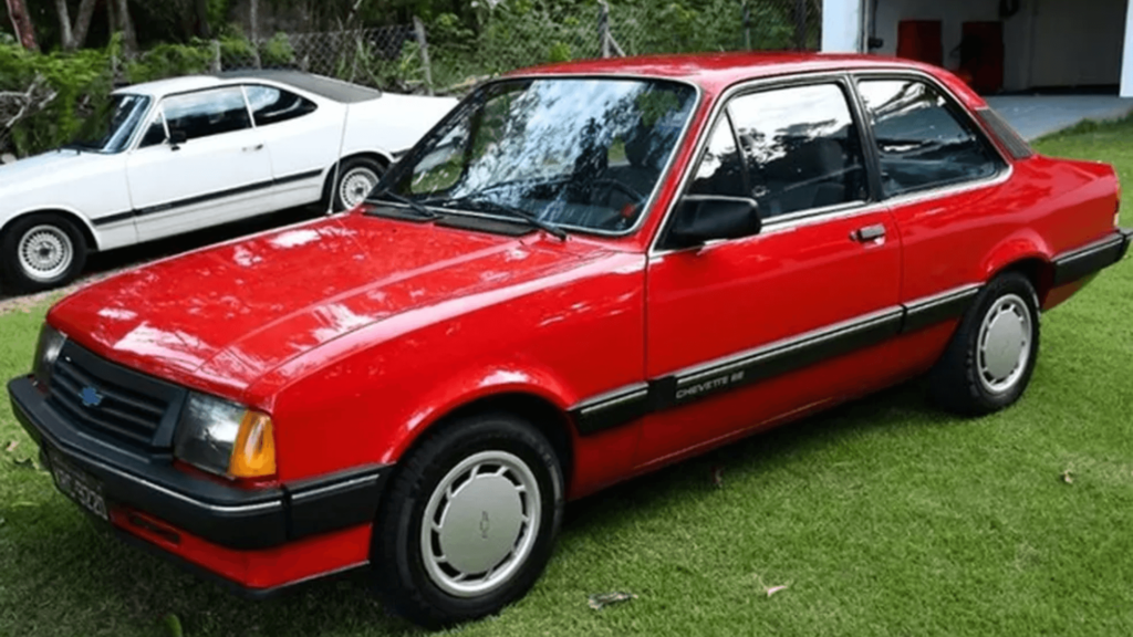 Chevrolet Chevette vermelho parado em cima de um gramado.