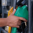 Pessoa segurando uma pistola verde de uma bomba de gasolina.