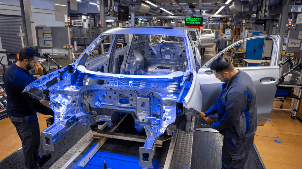 Duas pessoas trabalhando em um carro que está sendo fabricado.