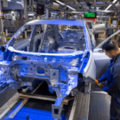 Duas pessoas trabalhando em um carro que está sendo fabricado.