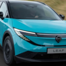 Nissan Leaf 2026 azul em movimento na estrada com os faróis acesos.